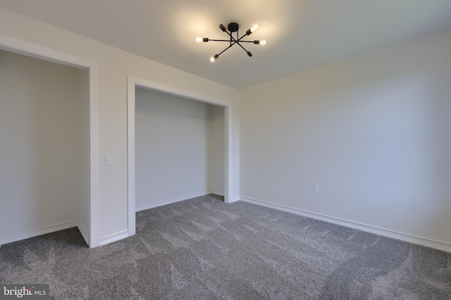 unfurnished bedroom featuring an inviting chandelier and dark carpet