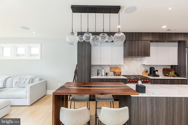 kitchen with light wood-type flooring, a kitchen breakfast bar, modern cabinets, open floor plan, and backsplash