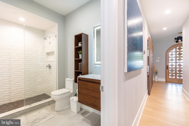 bathroom featuring hardwood / wood-style floors, vanity, toilet, and tiled shower