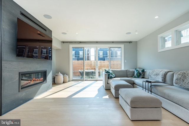 living room with a glass covered fireplace, recessed lighting, and wood finished floors