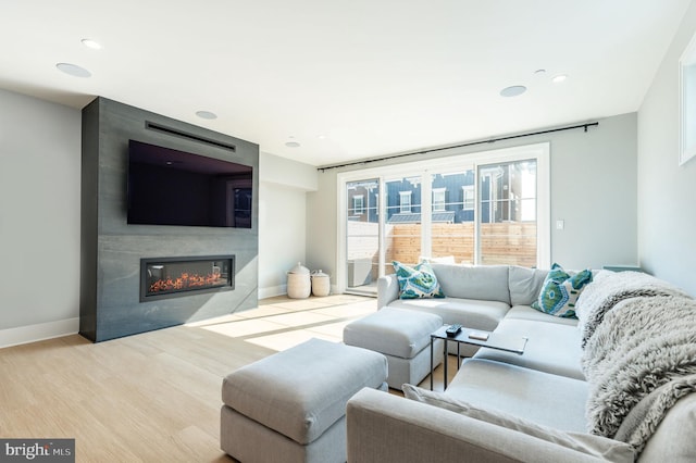 living room with recessed lighting, baseboards, wood finished floors, and a fireplace