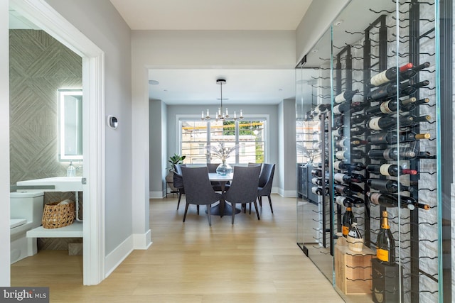 wine room with a notable chandelier, light hardwood / wood-style floors, and tile walls