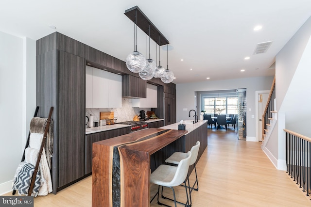 kitchen with a center island with sink, decorative light fixtures, and light hardwood / wood-style flooring