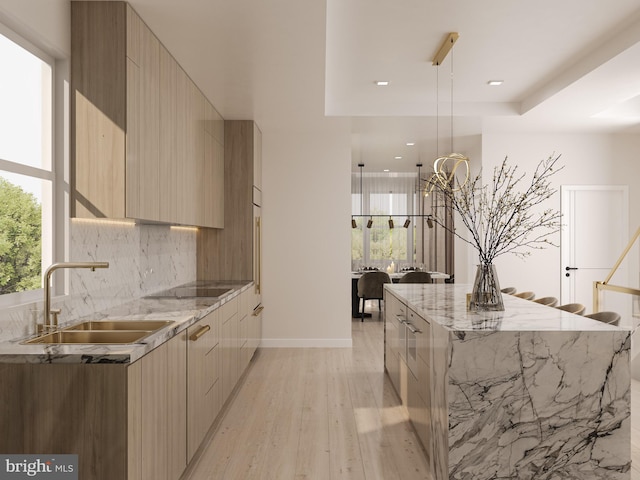 kitchen featuring backsplash, a tray ceiling, a large island, modern cabinets, and a sink