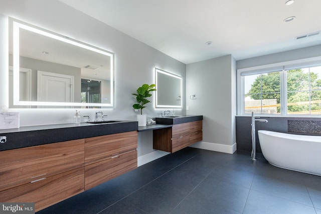 full bathroom with vanity, visible vents, baseboards, a freestanding tub, and tile patterned flooring