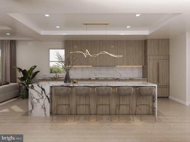 kitchen with light wood-type flooring, a tray ceiling, decorative backsplash, modern cabinets, and paneled fridge