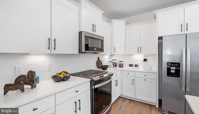 kitchen featuring backsplash, white cabinetry, light hardwood / wood-style floors, and stainless steel appliances