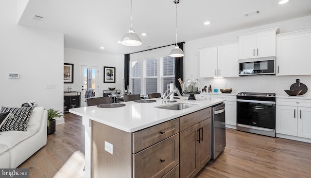 kitchen with sink, stainless steel appliances, hardwood / wood-style flooring, and white cabinets