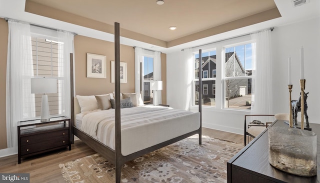 bedroom with hardwood / wood-style floors and a tray ceiling