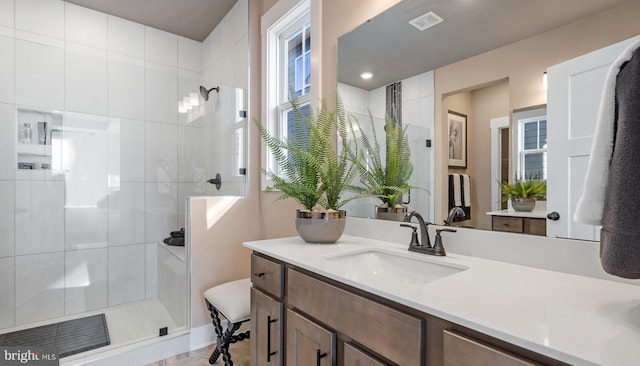 bathroom featuring a shower with shower door and vanity with extensive cabinet space