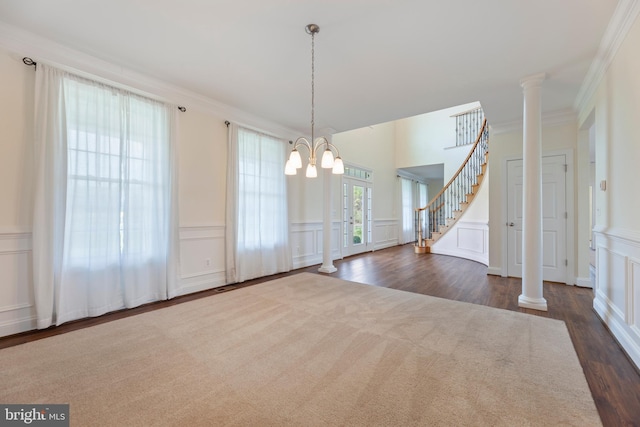 interior space featuring crown molding, dark carpet, a notable chandelier, and ornate columns