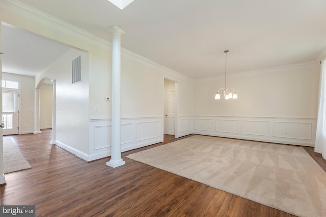 unfurnished room featuring crown molding, light hardwood / wood-style floors, a notable chandelier, and ornate columns