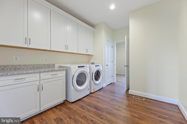 washroom featuring washer and clothes dryer, cabinets, and dark hardwood / wood-style flooring