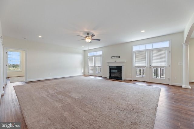 unfurnished living room with french doors, ornate columns, ceiling fan, and light hardwood / wood-style flooring