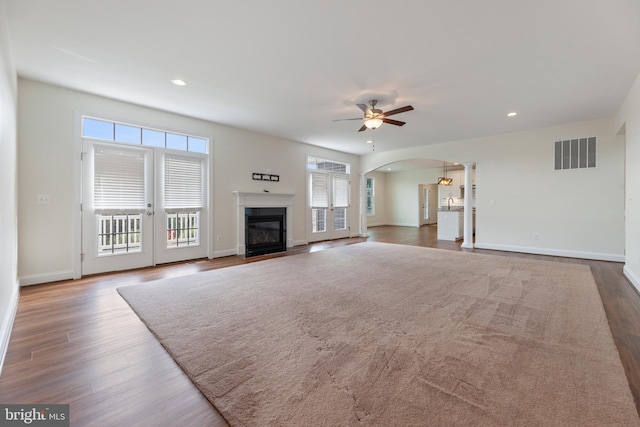 unfurnished living room with dark hardwood / wood-style flooring and ceiling fan