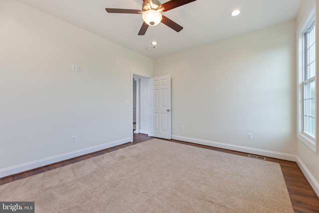 spare room with dark carpet and ceiling fan