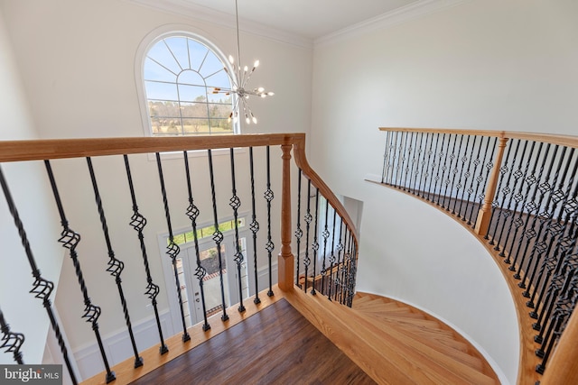 stairway featuring ornamental molding, a notable chandelier, and wood-type flooring