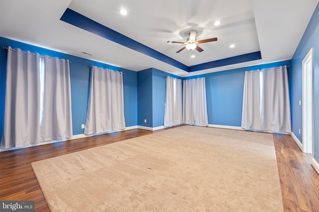 spare room featuring ceiling fan, a raised ceiling, and dark wood-type flooring