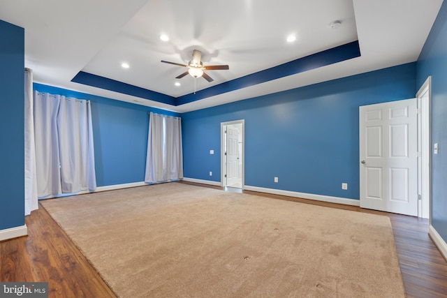 empty room featuring ceiling fan, dark wood-type flooring, and a raised ceiling