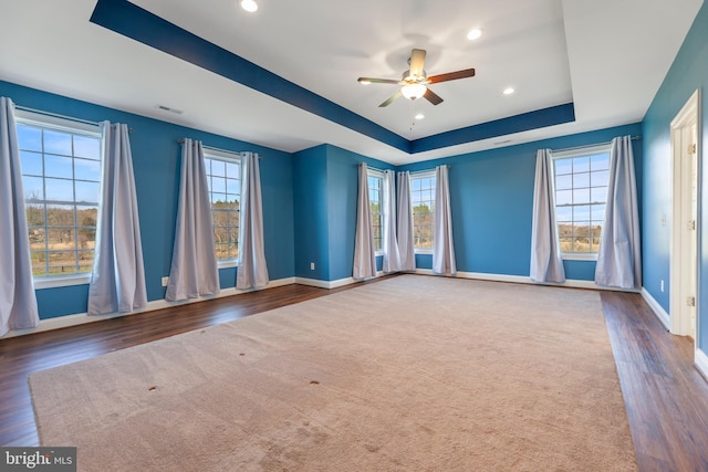 unfurnished room featuring plenty of natural light, a tray ceiling, ceiling fan, and dark hardwood / wood-style floors