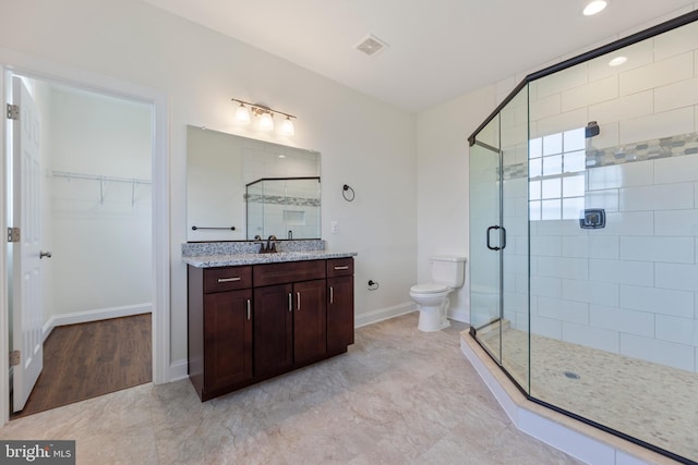 bathroom with vanity, toilet, a shower with shower door, and hardwood / wood-style flooring