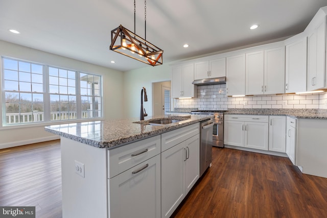 kitchen with light stone countertops, a center island with sink, dark hardwood / wood-style floors, and white cabinetry