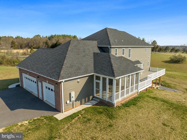 exterior space featuring a lawn, a sunroom, and a garage