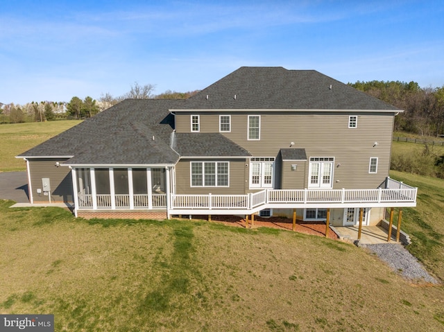 rear view of house with central air condition unit, a deck, a sunroom, and a lawn