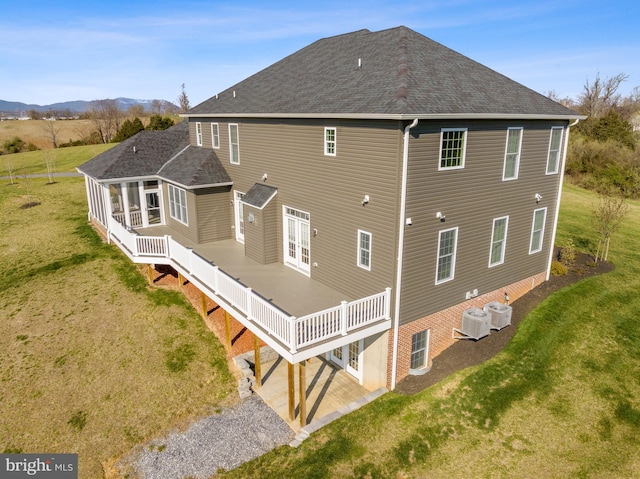 rear view of property featuring a wooden deck, a yard, and central AC