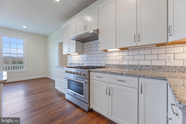 kitchen featuring luxury stove, light stone countertops, backsplash, dark wood-type flooring, and white cabinets