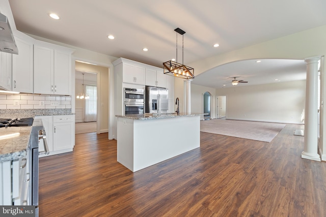 kitchen featuring dark hardwood / wood-style floors, a kitchen island, stainless steel appliances, ceiling fan with notable chandelier, and white cabinetry