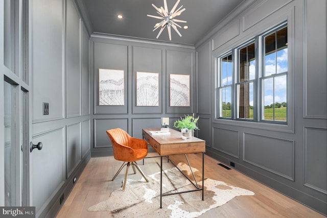 home office featuring visible vents, light wood finished floors, crown molding, a decorative wall, and a notable chandelier