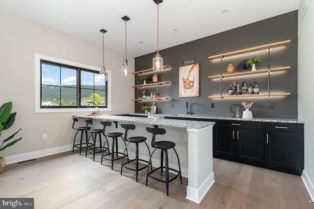 bar with wet bar, light wood-style flooring, baseboards, and visible vents