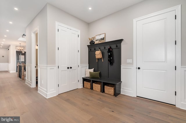 mudroom with a wainscoted wall, light wood-type flooring, recessed lighting, an inviting chandelier, and a decorative wall