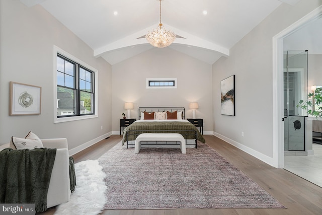 bedroom with baseboards, vaulted ceiling, ensuite bathroom, wood finished floors, and a notable chandelier