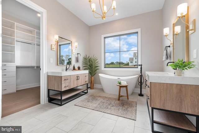 bathroom featuring a sink, baseboards, an inviting chandelier, and two vanities