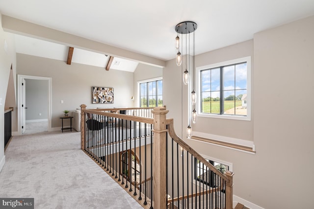 corridor with an upstairs landing, vaulted ceiling with beams, baseboards, and carpet floors