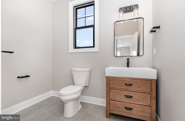 half bath featuring vanity, tile patterned floors, toilet, and baseboards