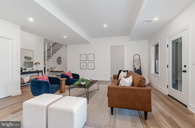 living area featuring recessed lighting, visible vents, light wood finished floors, and stairway