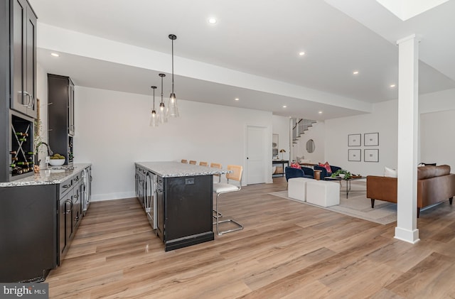 kitchen featuring open floor plan, a breakfast bar, and light wood-style flooring