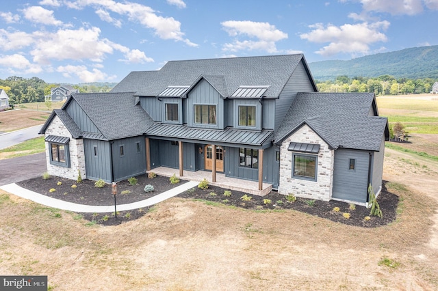 modern farmhouse featuring board and batten siding, a shingled roof, covered porch, metal roof, and a standing seam roof