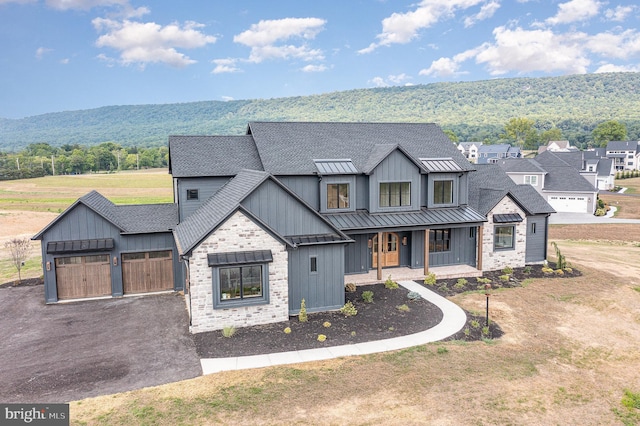 modern farmhouse with a standing seam roof, a porch, a shingled roof, board and batten siding, and metal roof