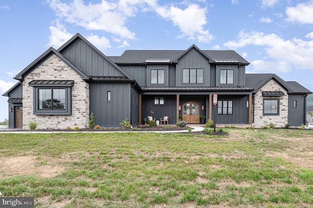 modern farmhouse featuring a front yard, a standing seam roof, a shingled roof, board and batten siding, and metal roof