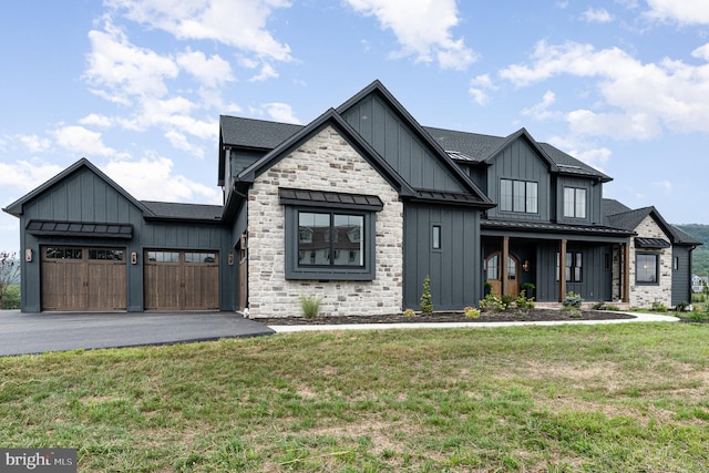 modern farmhouse featuring board and batten siding, metal roof, driveway, an attached garage, and a standing seam roof