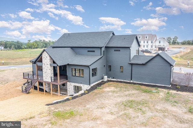 back of property with roof with shingles, a deck, and stairs