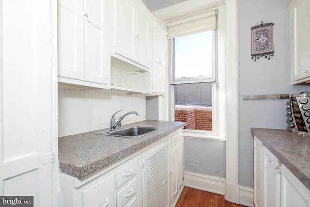 kitchen with sink, white cabinets, and wood-type flooring