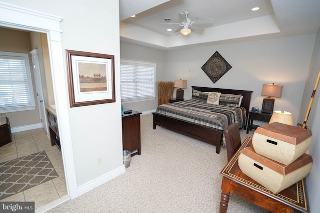 tiled bedroom featuring multiple windows, a tray ceiling, and ceiling fan