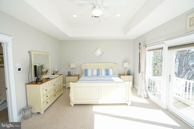 carpeted bedroom with ceiling fan, a raised ceiling, and access to outside