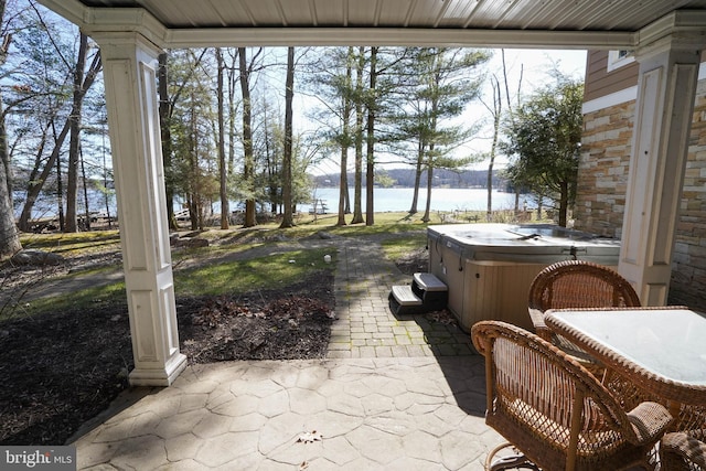 view of patio with a water view and a hot tub