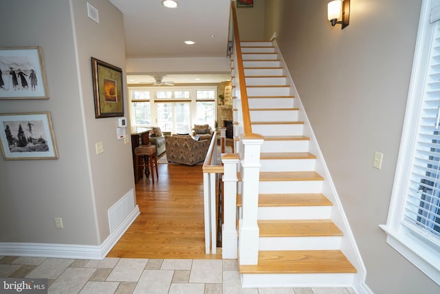 staircase featuring wood-type flooring and ceiling fan